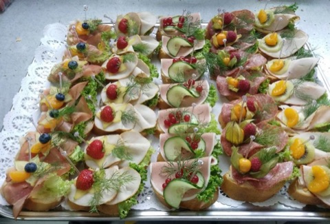 Ausgarnierte halbe Brötchen mit Wurst, Käse, Ei und Gemüse auf einer Platte